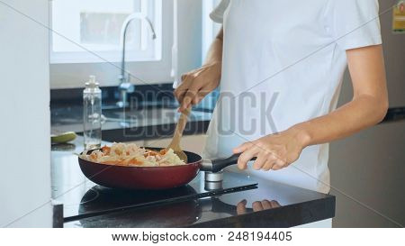 Woman Mixing Ingredients While Cooking Vegetarian Dish In The Frying Pan At Domestic Kitchen, Close-