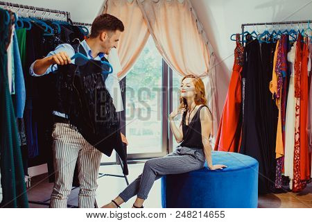 Young Attractive Woman Choosing A New Stylish Dress For Herself, Male Couturier Helps Her To Make A 