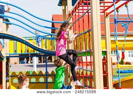 Girldren On Playground. Girl Climbing The Net