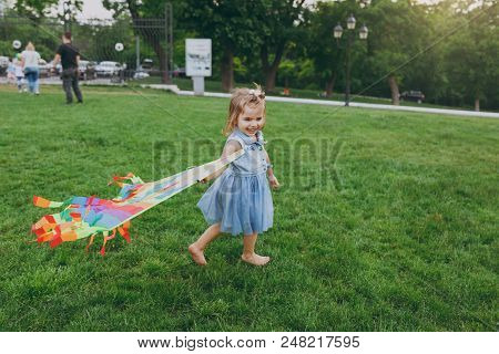 Laughing Little Cute Child Baby Girl In Denim Dress Walking, Play With Colorful Kite And Have Fun In