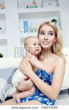 Happy mamm tenderly embracing her small baby at home. Family concept. Healthcare, pediatrics.