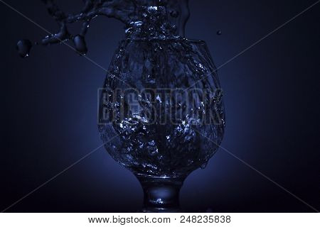 Simple Still-life Photo Of Whisky Glass, Water Jet And Dim Colour Light