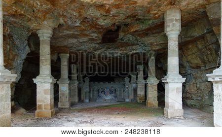 A Long Corridor Surrounded By Columns Ending In A Religious Monument.
