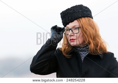 Portrait Of Woman In Glasses And Black Coat. Concentrated Rad Hair Woman In Hat. Portrait Of Busines