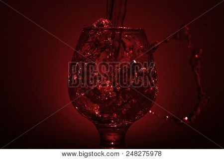 Simple Still-life Photo Of Whisky Glass, Water Jet And Dim Red Light