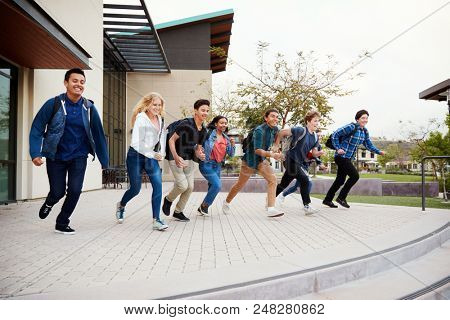 Group Of High School Students Running Towards Steps Outside College Buildings