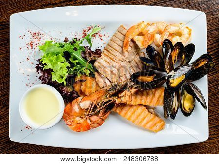 Delicious Seafood Dish. Fish Fillet, Mossels And Prawn Served With Appetizing Sauce In The White Pla