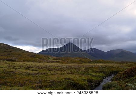 Lush Grass Fields With Large Mountains In The Background