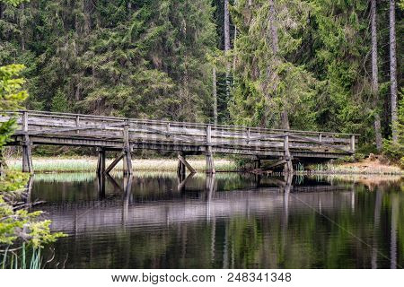 Wood Bridge Over A Lake Between Trees With Refelection