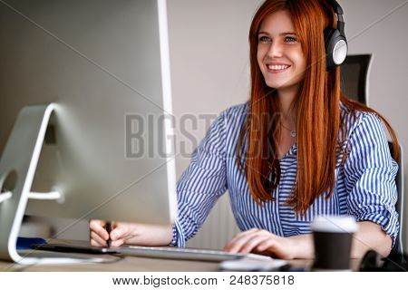 Smiling girl at working place reattaching and listening music