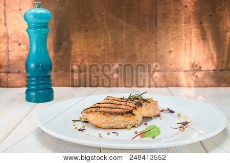 Tasty Cooked Steak On A White Plate, On Awooden Table. Brown Background, Blue Pepperbox.