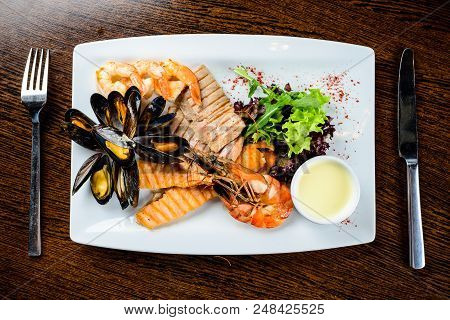 Delicious Seafood Dish. Fish Fillet, Mossels And Prawn Served With Appetizing Sauce In The White Pla