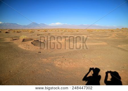 Shadow Of Two Tourists On The Ground Of Aldea De Tulor Ancient Village, San Pedro De Atacama Of Nort