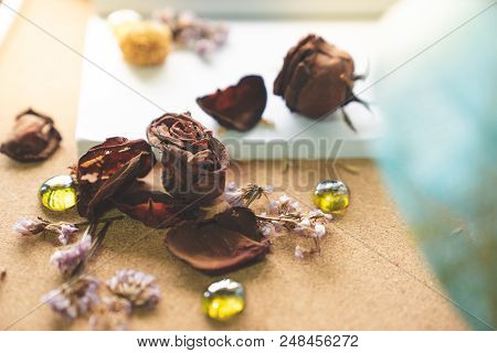 Withered Old Rusty Brown Roses And Love Word  On Blank White Book With Blurry Glasses And Blue Bouqu