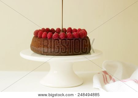 Chocolate Brownie Cake With Raspberries And Chocolate Icing On A Light Background. Selective Focus.