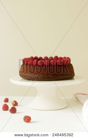 Chocolate Brownie Cake With Raspberries And Chocolate Icing On A Light Background. Selective Focus.