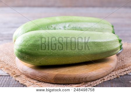 Courgettes Zucchini On Cutting Board On Wooden Table
