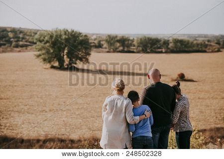 A Happy Family Is Standing In The Nature At Sunset In The Evenin