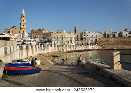 Monopoli, Italy - July 2 2018: People Swimming On Beach Porta Vecchia Near Cathedral During Sunrise