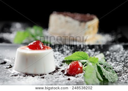 Photo Of Italian Panna Cotta Dessert With Strawberry Sirup And Mint Leaf On The Black Wooden Backgro