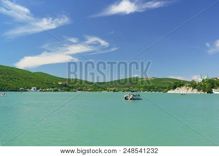 Tourists Ride On A Small Boat On The Picturesque Mountain Lake Abrau. Sunny Summer Day