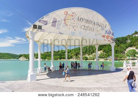 Vacationers On The Waterfront Of The Picturesque Mountain Lake Abrau In The Shadow Of The Music Scen