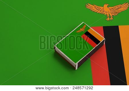 Zambia Flag  Is Pictured On A Matchbox That Lies On A Large Flag.