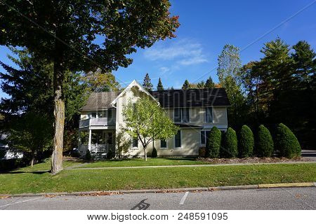 A Large Yellow Two Story Victorian Cottage, With A Balcony Over Its Wraparound Porch, In Bay View, M
