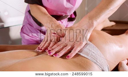 Massage Concept. Beautiful Young Woman Reciving Relaxing Massage At Luxury Spa Salon With Warm Cozy 
