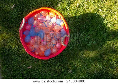 A Bucket Full Of Water Balloons Sitting In The Grass Ready For Summer Fun