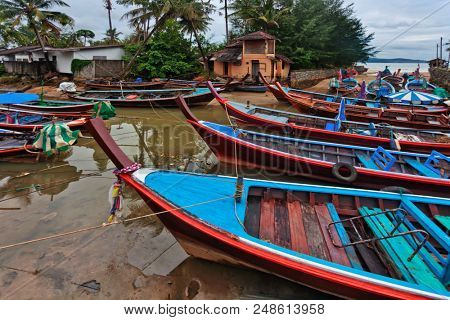 Long-tail boats under gloomy dramatic sky parking at Bang Tao Beach. Phuket. Thailand 