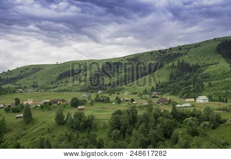 Photo Of Mountain Village In The Summer Under Beautiful Cloudy Sky. Ukraine, Carpathians, Dzembronia