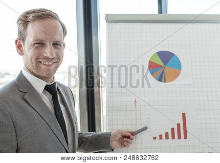 Business Man Making Presentation Of Reports In Diagrams And Graphs At Flip Chart In Offfice