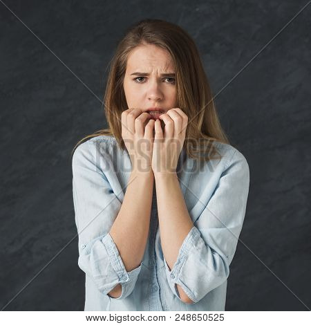 Young Nervous Girl Biting Her Nails, Worried Of Making Mistake, Black Studio Background
