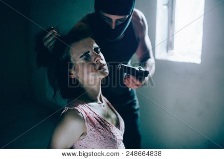 Portrait Of Cruel Kidnapper Holding Girl's Hair In Hand And Holding Gun Very Close To His Face. He W