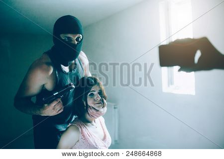 Angry Kidnapper Is Holding Girl's Head With Lefy Hand And Gun In Another One. He Is Looking On Camer