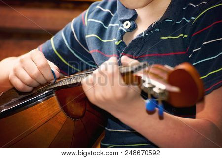 The Boy Plays The Guitar And Takes Chords, Dombra On The Background Of The Piano.