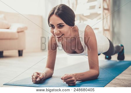 Young Smiling Woman Doing Exercises On Mat At Home. Pretty Girl Training At Home. Indoor Fitness. Ex