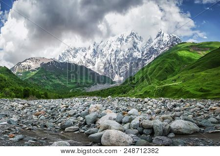 Perfect Mountain Landscape In Georgia, Svaneti. Green Hills, Snowy Rocks Mounts And Stones On River 