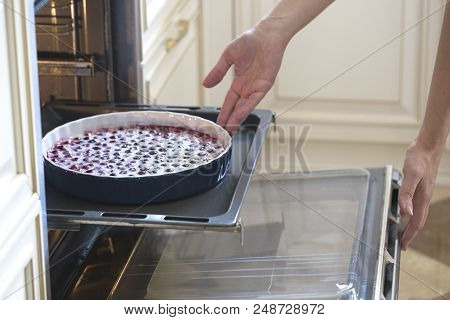 Woman Cooking In The Kitchen, Puts Cakes In The Oven. Clafoutis Cherry Pie. Preparation Of A French 