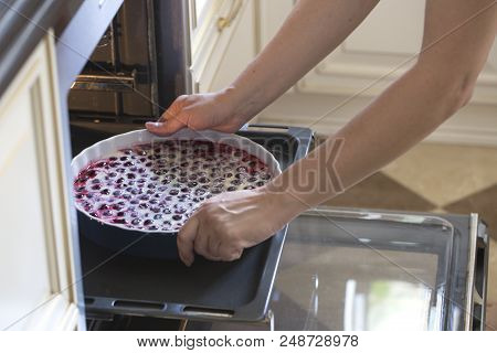 Woman Cooking In The Kitchen, Puts Cakes In The Oven. Clafoutis Cherry Pie. Preparation Of A French 