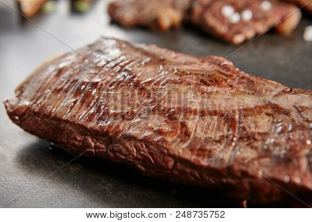 Hot Grilled Whole Flank Steak on Black Stone Background. Fresh Juicy Medium Rare Beef Grillsteak. Barbecue Meat Close Up