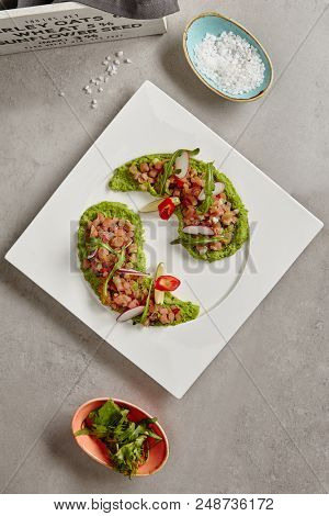 Ahi Tuna Seviche with Radish Slices and Rucola on White Plate Top View. Raw Fish Fillet Called Cebiche Marinated in Lime Juice as Traditional South American Cuisine