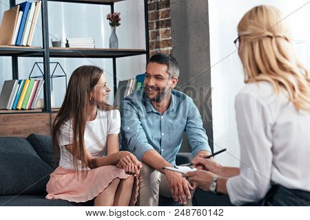 Rear View Of Female Counselor Taking Notes In Clipboard On Therapy Session Of Couple