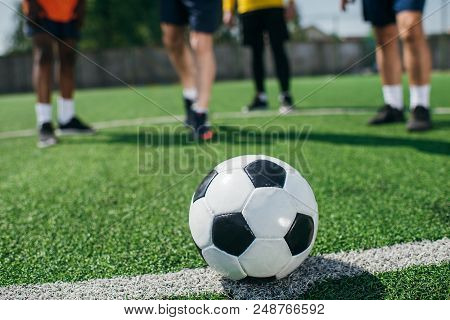 Selective Focus Of Football Ball And Multicultural Elderly Men On Green Football Field