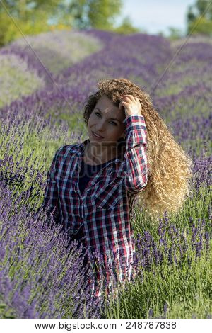 Ostrow, Poland - June 6, 2018: Beautiful  Woman With Long Curly Hair In The Middle Of A Lavender Fie