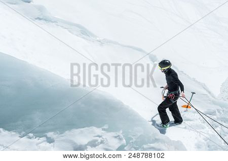 A Professional Mountaineer In A Helmet And Ski Mask On Insurance Makes A Nick-hole In The Glacier Ag