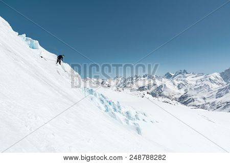 A Professional Mountaineer In A Helmet And Ski Mask On Insurance Makes A Nick-hole In The Glacier Ag
