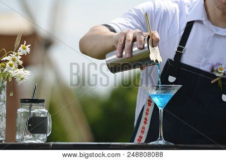 Bartender Workplace. Bartender On The Street Catering Bar Preparing A Coctail In A Martini Glass, Se