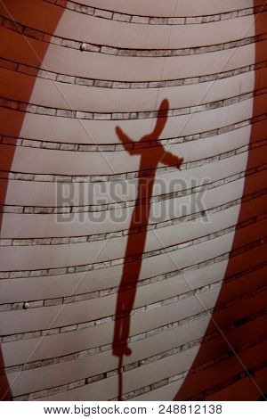 Silhouette Of Gymnast On Wall. Shadow Of Gymnast Of Balancing Actor Performing Number High Above Cir